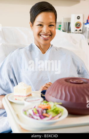 Frau im Krankenhausbett mit einem Tablett mit Essen Stockfoto