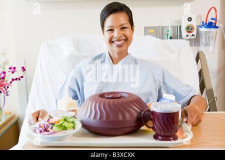 Frau im Krankenhausbett mit einem Tablett mit Essen Stockfoto