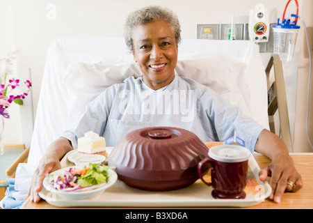 Ältere Frau im Krankenhausbett mit einem Tablett mit Essen Stockfoto