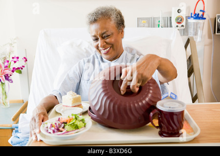 Ältere Frau im Krankenhausbett mit einem Tablett mit Essen Stockfoto