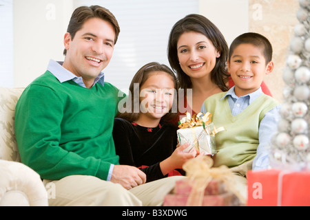 Familie Zusammensitzen auf Sofa, hält ein Weihnachtsgeschenk Stockfoto