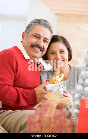 Applying paar auf Sofa hält Weihnachtsgeschenk Stockfoto