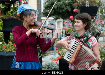 Zwei junge Frauen auf der Straße in Aberystwyth Wales UK spielen Violine und Akkordeon Squeeze Box als Straßenmusikant Stockfoto