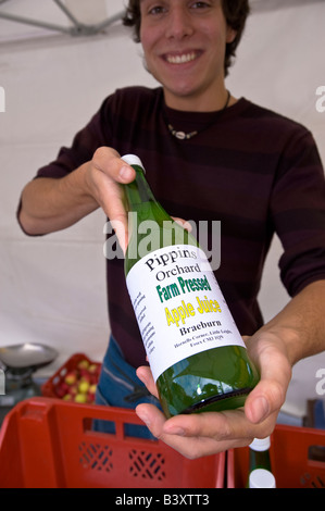 Lächelnde Verkäufer bietet frisch gepresst Apfelsaft Acton Food Festival Acton W3 London Vereinigtes Königreich Stockfoto