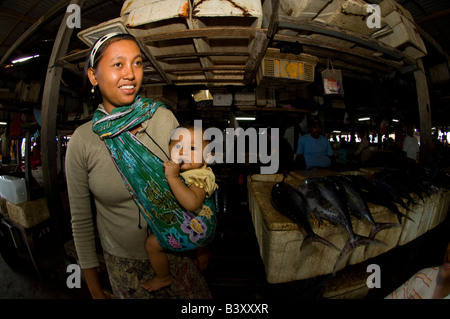 Eine Frau trägt ihr Kind im Tragetuch auf dem Fischmarkt in Denpasar Bali Indonesien Stockfoto