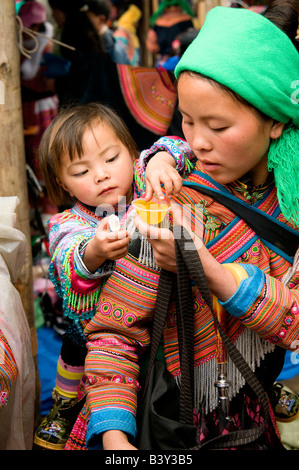 Eine Blume Hmong-Mutter mit ihrem Baby auf dem Rücken in Sapa Markt Nord-Vietnam Stockfoto