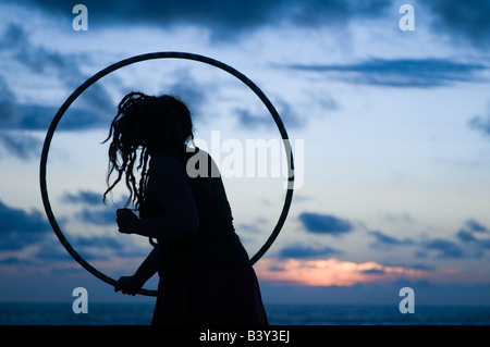 Junges Mädchen Durchführung Zirkus Fähigkeiten Routine mit ihrer Hula-Hoop bei Sonnenuntergang am Meer Aberystwyth Wales UK Stockfoto