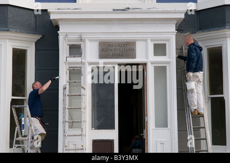 zwei Maler stehen auf Leitern Anstrich der Fassade außerhalb eines Gebäudes Stockfoto