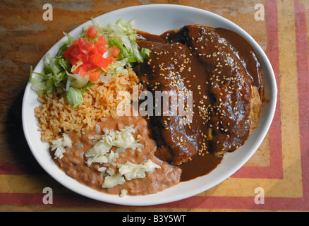 Chicken Enchiladas mit einer Mole Poblano Sauce und Reis und Bohnen. Stockfoto