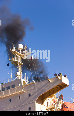 Schwarzer Rauch steigt vom Schiff des Trichters nähert sich das Schiff am Kai. Stockfoto