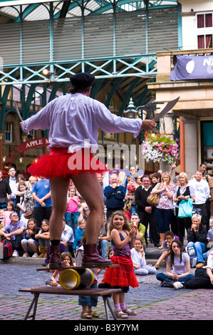 Straßenkünstler unterhält, Touristen und Passanten Covent Garden London Vereinigtes Königreich Stockfoto