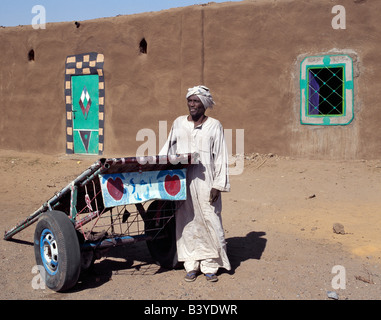 Sudan, Sahara Wüste Qubbat Selim. Ein nubischer Mann steht neben seinem Esel gezogenen Karren in einem Quadrat am Qubbat Selim. Dieses Dorf, Stockfoto