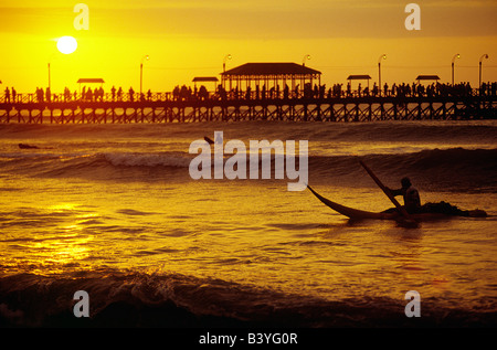 Peru, La Libertad, Huanchaco. Ein Pescador (Fischer) wartet auf eine Welle ans Ufer auf seinem Boot Reed in Huanchaco, im Norden Perus zu reiten. Die Fischer Reiten auf die Boote genannt Caballitos de Totora (kleine Pferde Schilf) und verwenden Sie ein Segment des Bambus für ein Paddel. Stockfoto