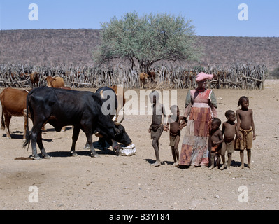 Namibia, Damaraland, Palmwag. Eine Herero-Frau führt ihren Kindern wieder nach Hause nach der Überprüfung auf die Familie Rinder. Die aufwendige Stockfoto