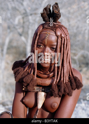 Namibia, Kaokoland, Empembe. Eine junge Himba-Frau in traditioneller Kleidung.  Ihr Körper glänzt aus einer Mischung von rotem Ocker, Butterfett Stockfoto