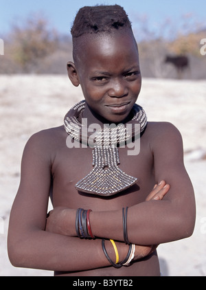 Namibia, Kaokoland, Empembe. Ein Himba-Mädchen hat ihr Haar in zwei Zöpfen, die üblichen Stil der jungen Mädchen bis zum Jugendalter. Ihr große, Runde weiße Perlen Halskette, genannt Ombwari, wird von beiden Geschlechtern getragen. Ihre anderen Hals-Ornament besteht aus Metall-Perlen auf Leder gesichert. Die Himba sind Bantu Herero sprechende Nomaden, die in der rauen, trockenen aber krass schöne Landschaft entlegenen Nordwesten Namibias Leben. Stockfoto