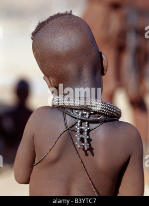 Namibia, Kaokoland, Epupa. Ein kleines Mädchen, ihre Körper verschmiert mit einer Mischung aus rotem Ocker, Butterfett und Kräuter, trägt eine Runde weiße Perlen Halskette, genannt Ombwari, und eine hintere Ornament, bekannt als Eha, aus Metall-Perlen. Die Himba sind Bantu Herero sprechende Nomaden, die in der rauen, trockenen aber krass schöne Landschaft entlegenen Nordwesten Namibias Leben. Stockfoto