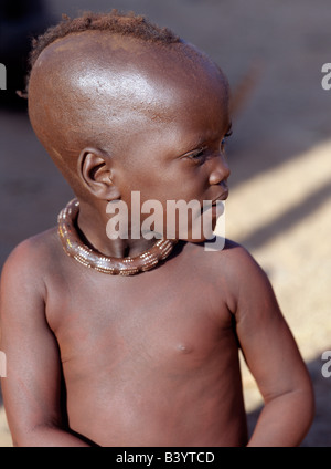 Namibia, Kaokoland, Epupa. Ein kleines Mädchen, ihre Körper verschmiert mit einer Mischung aus rotem Ocker, Butterfett und Kräuter, trägt eine Runde weiße Perlen Halskette, genannt Ombwari, eine Tradition der Himba ausgerechnet. Die Himba sind Bantu Herero sprechende Nomaden, die in der rauen, trockenen aber krass schöne Landschaft entlegenen Nordwesten Namibias Leben. Stockfoto