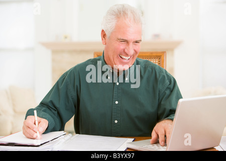 Mann im Speisesaal mit Laptop und Papierkram lächelnd Stockfoto