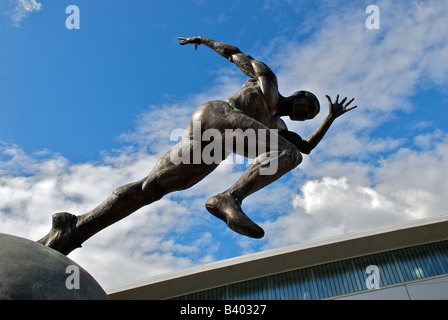 Bronzestatue eines Athleten auf einem Globus von Bildhauer Colin Spofforth, außerhalb SportsCity, Eastlands, City of Manchester Stadium Stockfoto