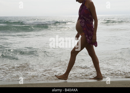 Eine Schwangere, die am Strand entlang läuft und Wasser spritzt, trägt eine Bluse über einem Badekostüm. Canet Plage bei Perpignan Südfrankreich 2008 Stockfoto