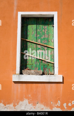 Mit Brettern vernagelt grünen Fensterläden in einem alten orange bemalten Gebäude Venedig Italien Stockfoto