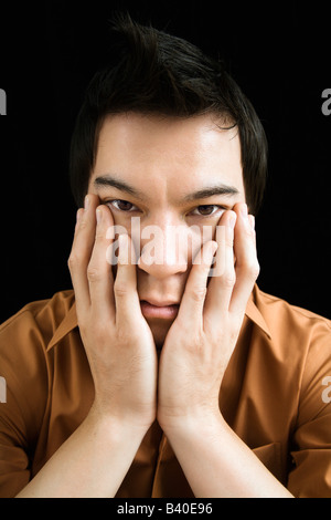 Porträt von asiatischen jungen Mann mit den Händen auf Gesicht Stockfoto