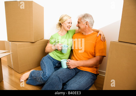 Mittleren gealterten paar am Boden unter Karton bewegen Boxen Kaffee trinken Stockfoto