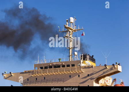 Schwarzer Rauch steigt vom Schiff des Trichters nähert sich das Schiff am Kai. Stockfoto