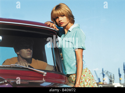 Junge Frau lehnt sich an ein Auto Mann sitzt im Inneren Stockfoto