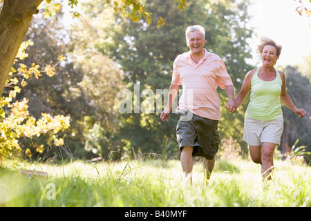 Paar im Park Hand in Hand laufen und lächelnd Stockfoto