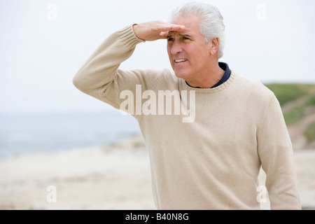 Mann am Strand Blick mit der Hand über die Augen Stockfoto