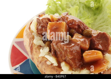 Gesund frisch gebackene Jacke Kartoffel gefüllt mit Rindfleisch Eintopf und Gemüse essen mit einen Freistellungspfad Menschen Stockfoto