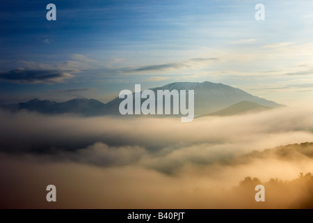 Nebel im Morgengrauen auf Piano Grande liegend, mit den Bergen Monti Sibillini Nationalpark erhebt sich über, Umbrien, Italien Stockfoto