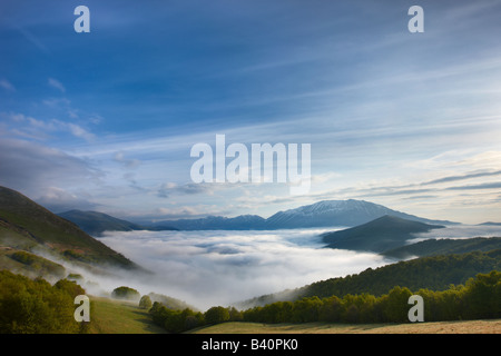 Nebel im Morgengrauen auf Piano Grande liegend, mit den Bergen Monti Sibillini Nationalpark erhebt sich über, Umbrien, Italien Stockfoto