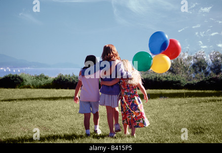 USA, Washington, Bellingham. Mädchen zu Fuß auf Rasen mit Luftballons. Stockfoto