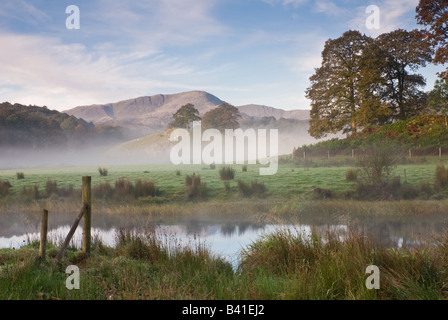 Nebligen Morgen auf den Fluß Brathay, mit Langdale Pfähle im Hintergrund. Stockfoto