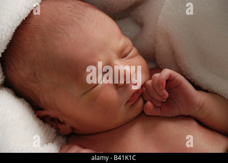 Eine Nahaufnahme Schuss eines schlafenden neugeborenen Jungen.  Schlafen mit der Hand durch Gesicht.  Neutrale Farben, weißen Hintergrund. Stockfoto