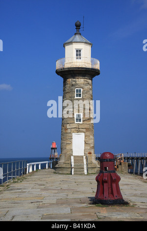 Stein-Leuchtturm und alten hölzernen Capstan auf Whitbys südlichen Pier, umrahmt von einem blauen Himmel Stockfoto