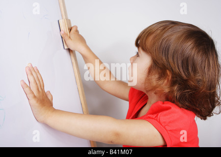 Eine zwei Jahre altes Kleinkind Mädchen ist ihre Zeichnung aus einem Whiteboard löschen. Stockfoto