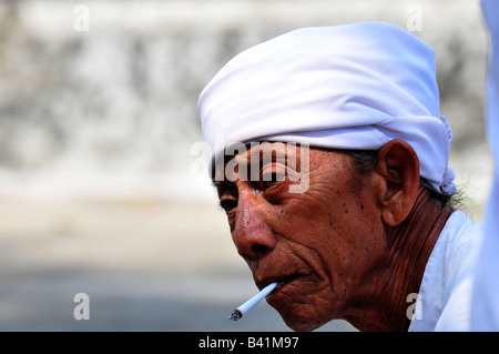 Manco (Dorfpfarrer) Rauchen, Zeremonie am Strand von Kusamba, Teil der Feuerbestattung Ritual, Bali, Indonesien Stockfoto