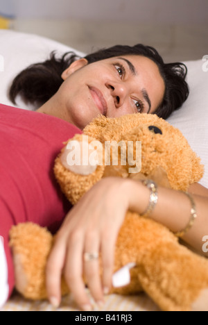Eine Latina Mutter legte sich in der Nähe von seinem Baby Teddy bear Stockfoto