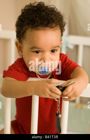 Ein Portrait eines Kleinkindes in seiner Wiege, ein Auto-Taste gedrückt halten. Stockfoto