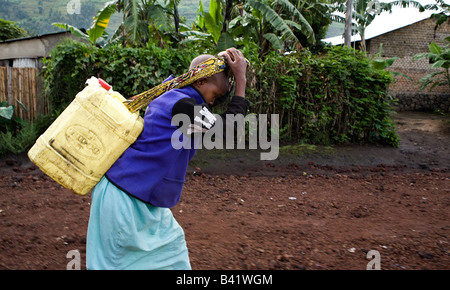 Ruandischen Mädchens führt Wasser aus dem Brunnen, einen anstrengenden Job als 20 Liter Kanister wiegt 44 Pfund, wenn Sie voll. Stockfoto