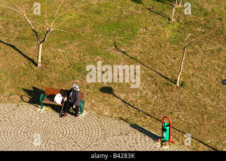 Alte Frau Taking A Atem auf einer Holzbank. Stockfoto