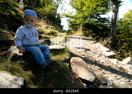 Kleine blonde Kind Junge sitzt auf Feldweg Berg Stockfoto