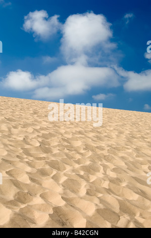 Sanddüne mit vielen menschlichen Fußabdrücke unter einem blauen Himmel mit weichen Wolken Stockfoto