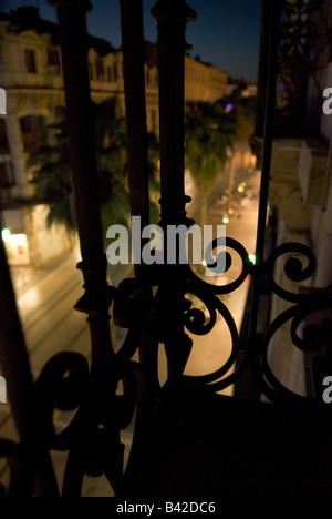 malerische Aussicht durch einen schmiedeeisernen Balkon eines Montpelliers Palm gesäumten Hauptstraßen in der Nacht Stockfoto