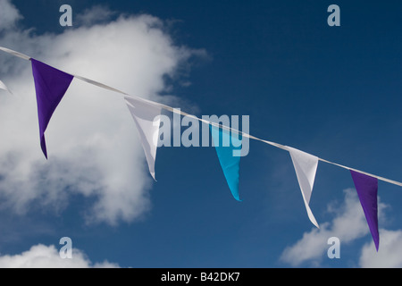 Party Girlanden Fahnen in verschiedenen Farben mit Wolken und blauer Himmel im Hintergrund. Stockfoto