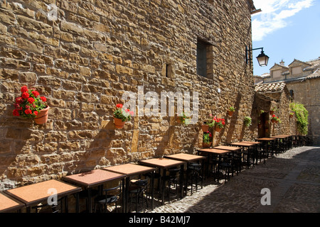 Restauranttische an der Plaza Mayor in Ainsa, Huesca, Spanien in den Pyrenäen, einer alten ummauerten Stadt mit Blick auf Hügel Cinca Stockfoto